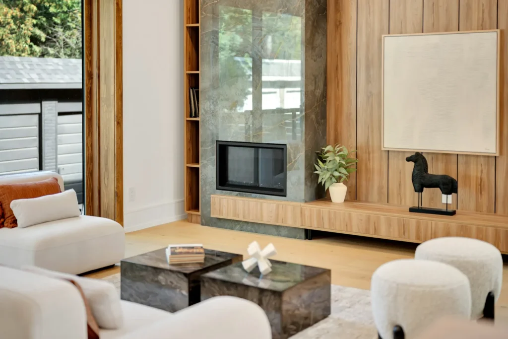 Modern fireplace built into a wood-paneled wall beside tall windows.